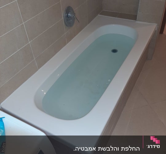 אמבטיה עם חיפוי אריחים ומים בתוכה